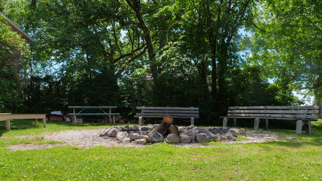 Stone fire pit ringed with benches by the lake