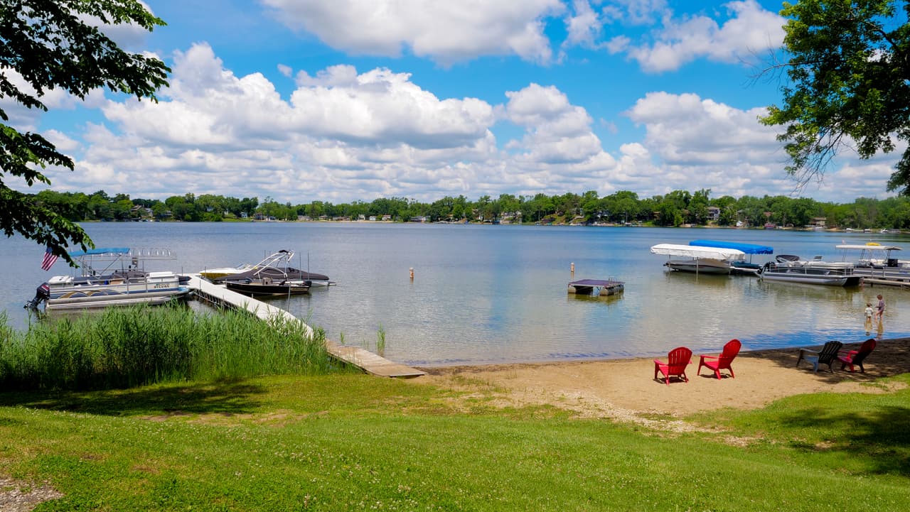 Sandy beach and red Adirondack chairs at the shoreline