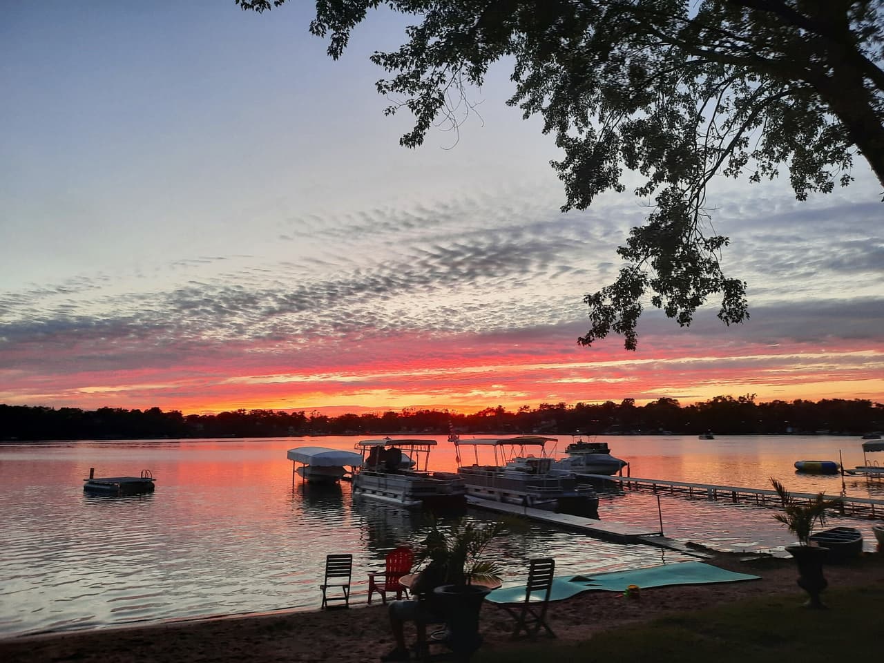 Sunset over Lily Lake from the beach, boats at the piers