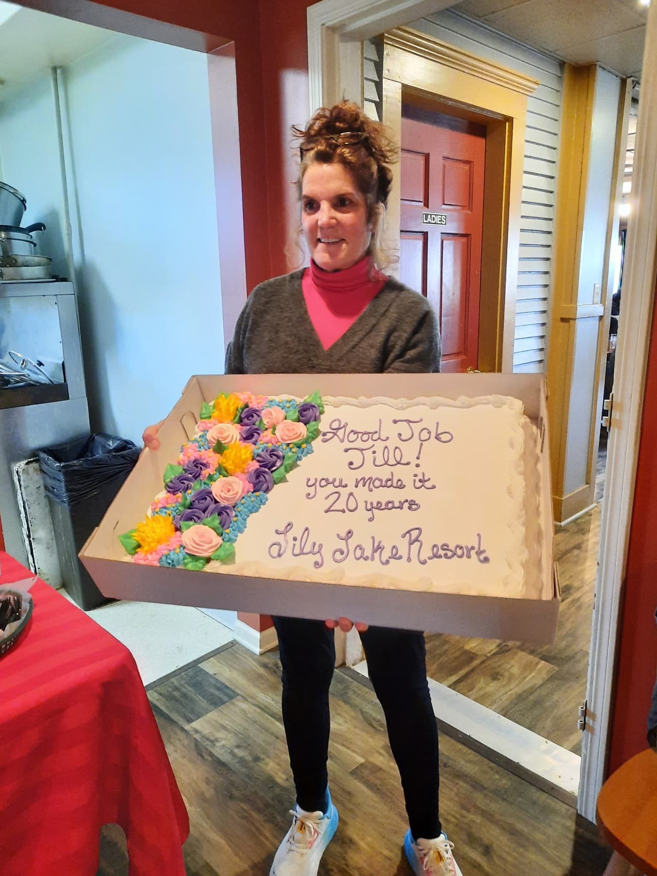 Jill holding a cake that reads "Good Job Jill, you made it 20 years"