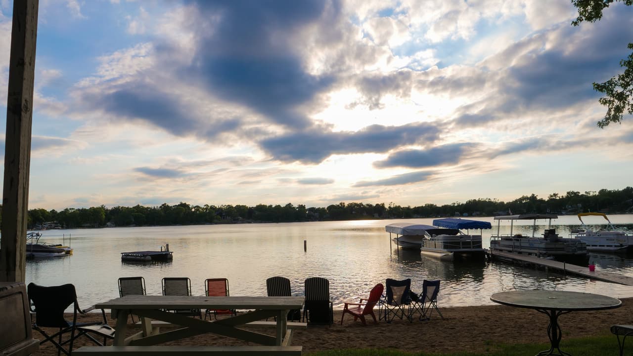 Lily Lake at golden hour from the Lily Lake Resort patio, picnic tables on the sand and pontoons at the pier