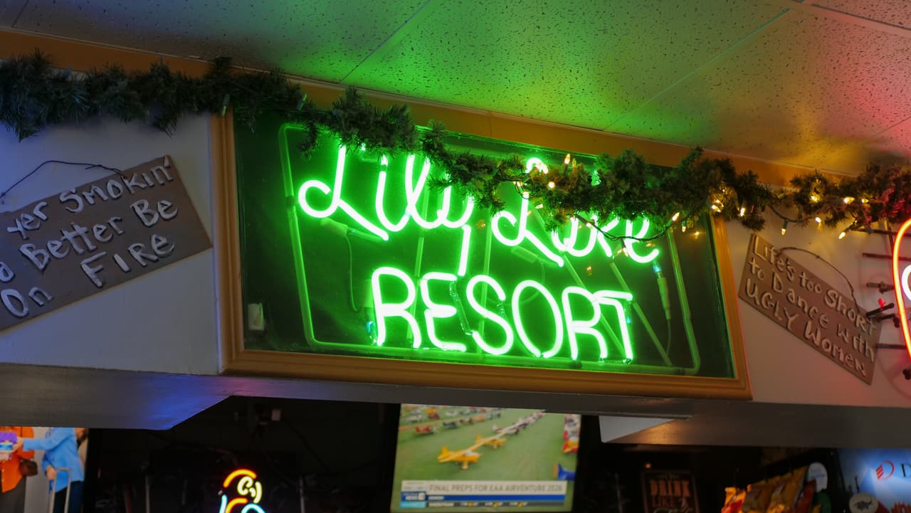 Green neon Lily Lake Resort sign above the bar
